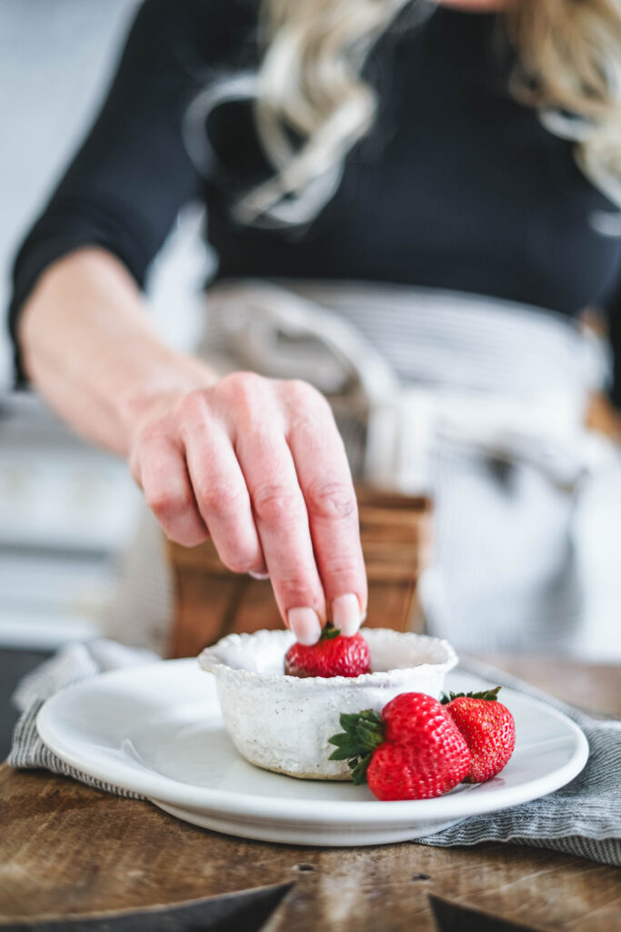 Dipping a strawberry in dark chocolate.