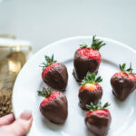 Delicious dark chocolate dipped strawberries on a white plate.