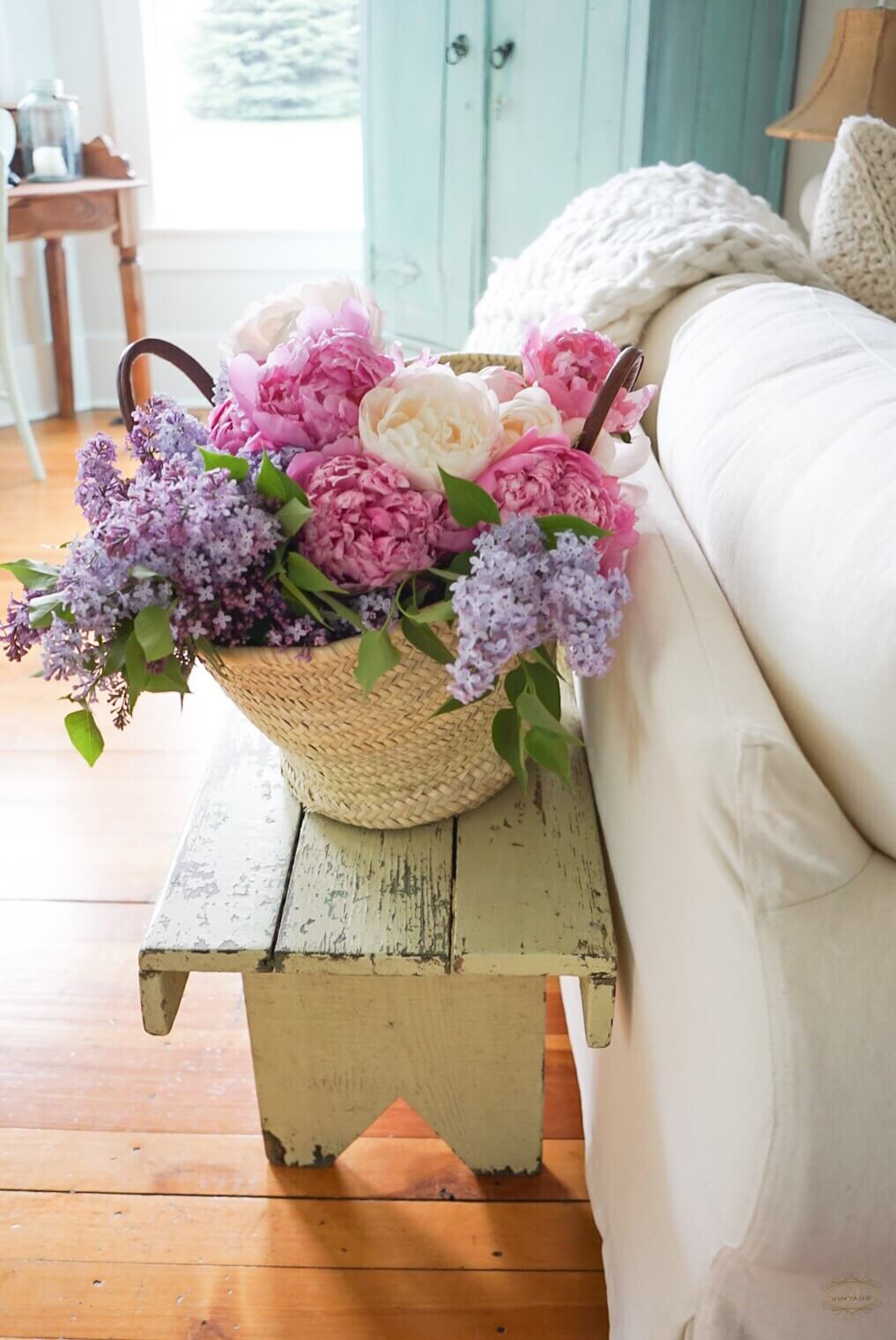peony lilac flowers in a market basket on a salvaged wood bench 