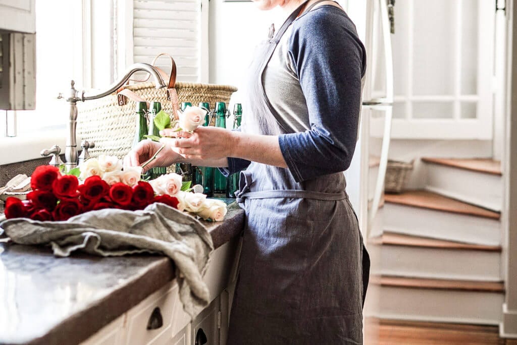 a girl cutting fresh roses at a farmhouse sink to make them last longer