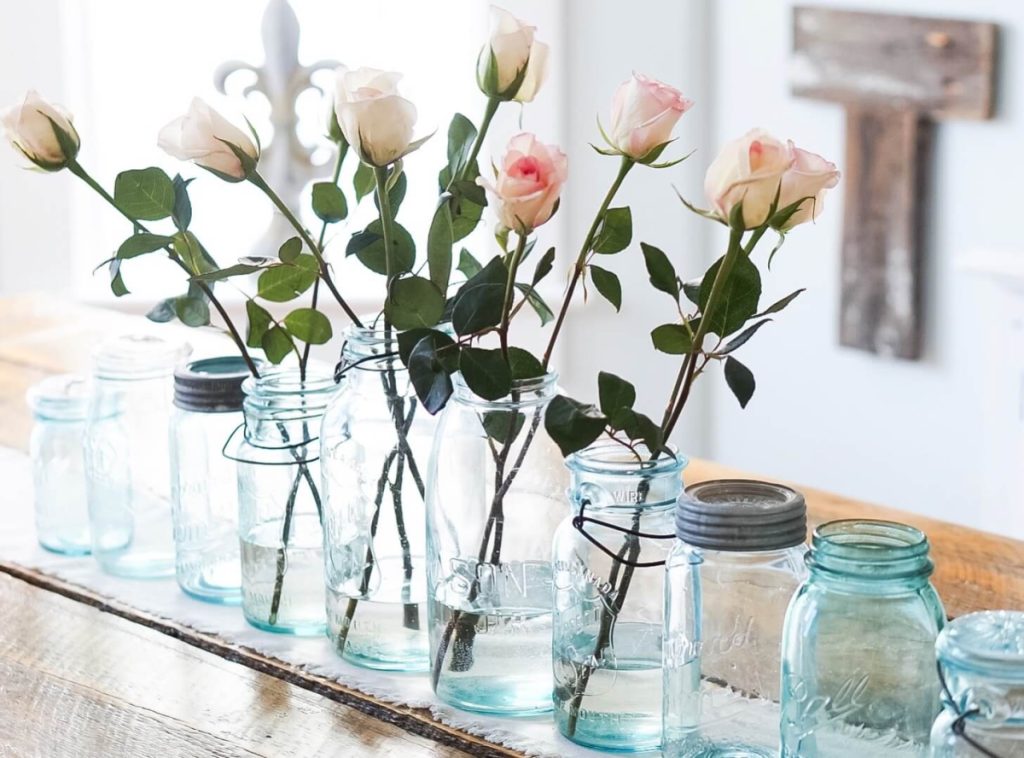 Pink Roses in vintage jars on a table.