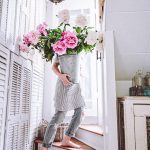 girl walking up stairs with a huge bucket of fresh cut peonies