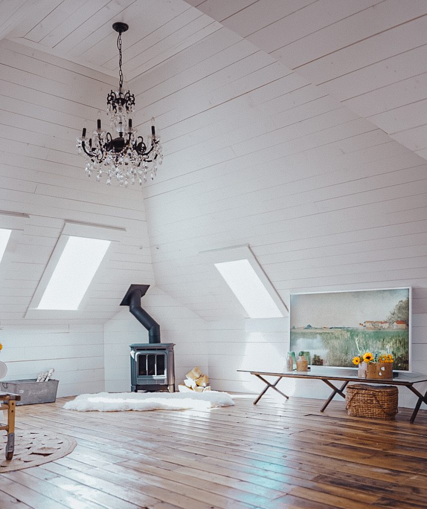 shiplap attic space with a free standing fire place and chandelier