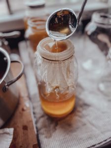 straining apple juice into a jar to can
