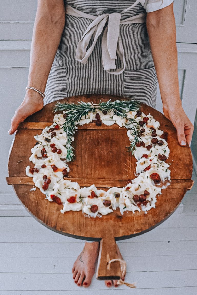 Lady holding a large holiday butter board wearing a linen apron