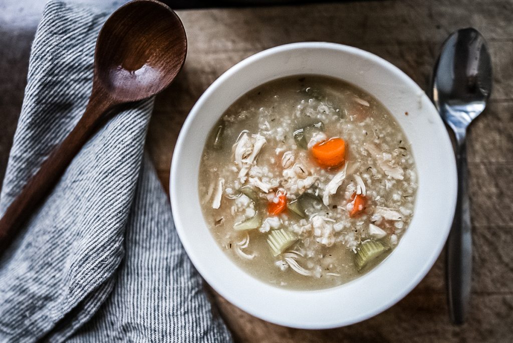 chicken barley soup with carrots in a white bowl