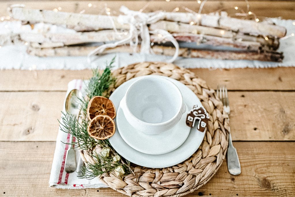 A holiday place setting with vintage ironstone, a gingerbread cookie and dried orange slices.