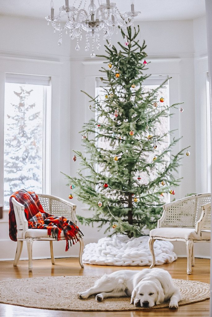 Scandinavian Christmas with a minimal Christmas tree and a chunky blanket used as a tree skirt