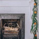 orange garland with fresh greenery on a fireplace mantle