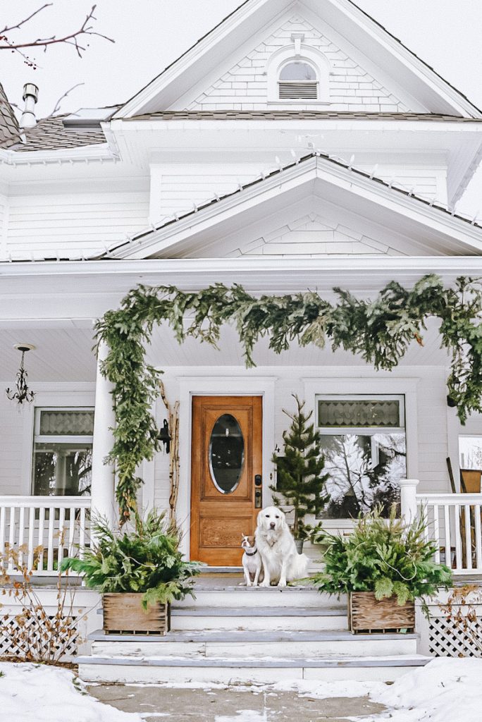 simple Scandinavian Christmas decorations on a front porch of a white house