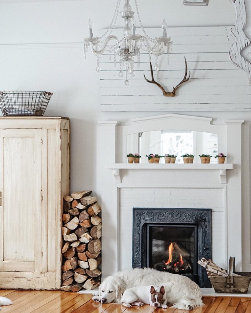 cozy fireplace decorated for winter with stacked wppd beside and birch logs