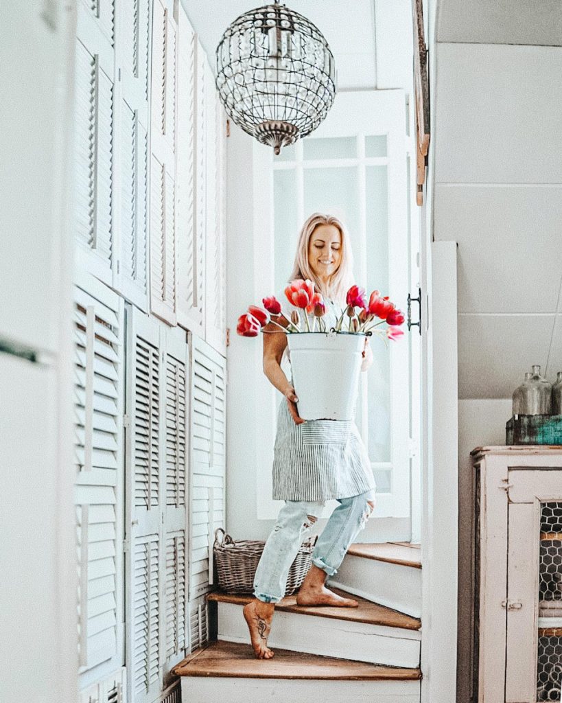 girl on a staircase carrying a bucket of flowers