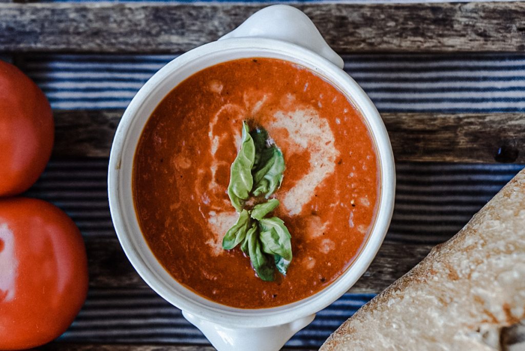 Homemade smoked tomato soup in a vintage bowl with basil on top.