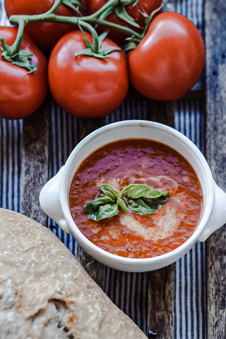 smoked tomato soup in an antique ironstone bowl beside tomatoes and fresh artisan bread