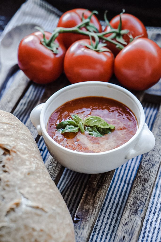 Delicious smoked tomato soup with basil on top in an ironstone bowl.