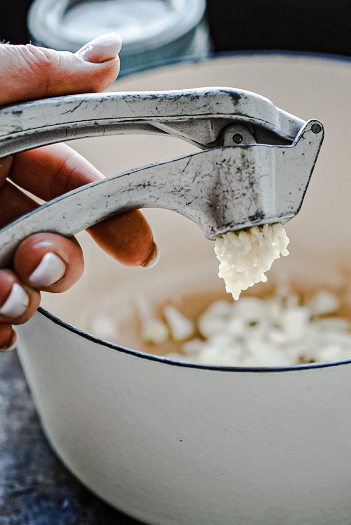 Mincing garlic to make soup out of tomatoes.