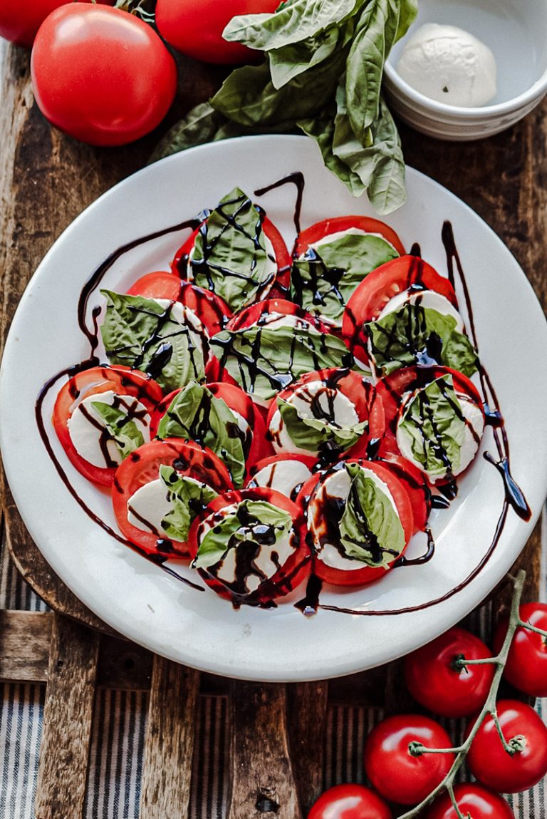 Tomato mozzarella basil salad with balsamic reduction on an ironstone plate garnished