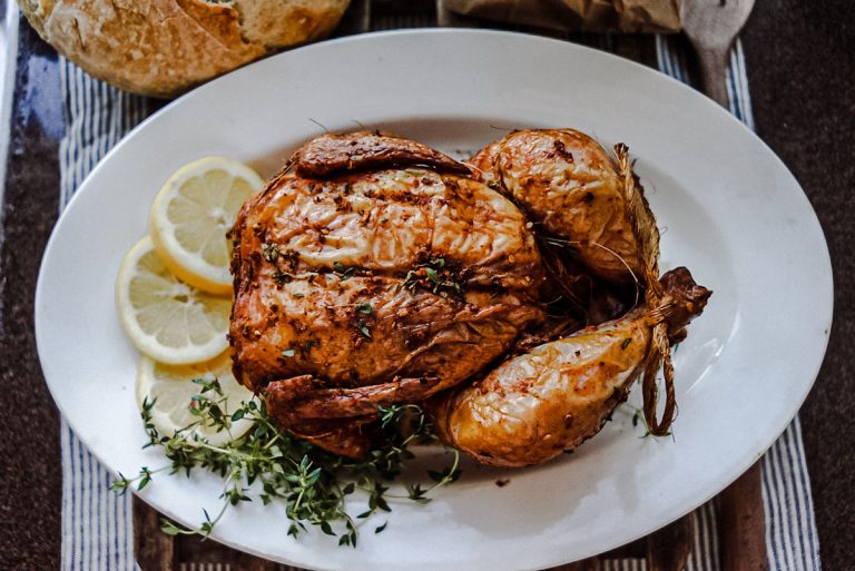 a smoked chicken on a platter with lemons and hebs