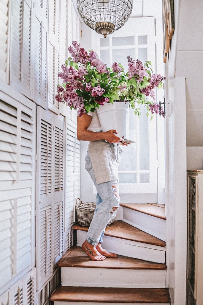 girl carrying a lilac bouquet up the stairs