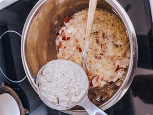 Adding flour to a pot to make béchamel for lasagna.