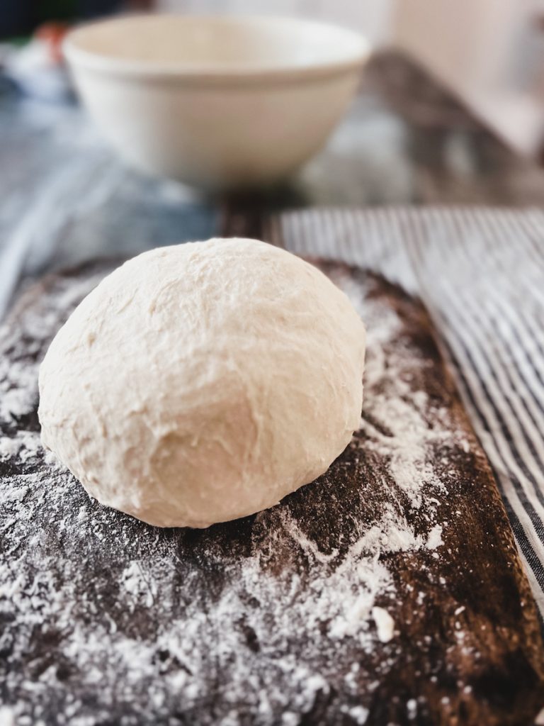 Artisan bread dough that is proofing on a cutting board.