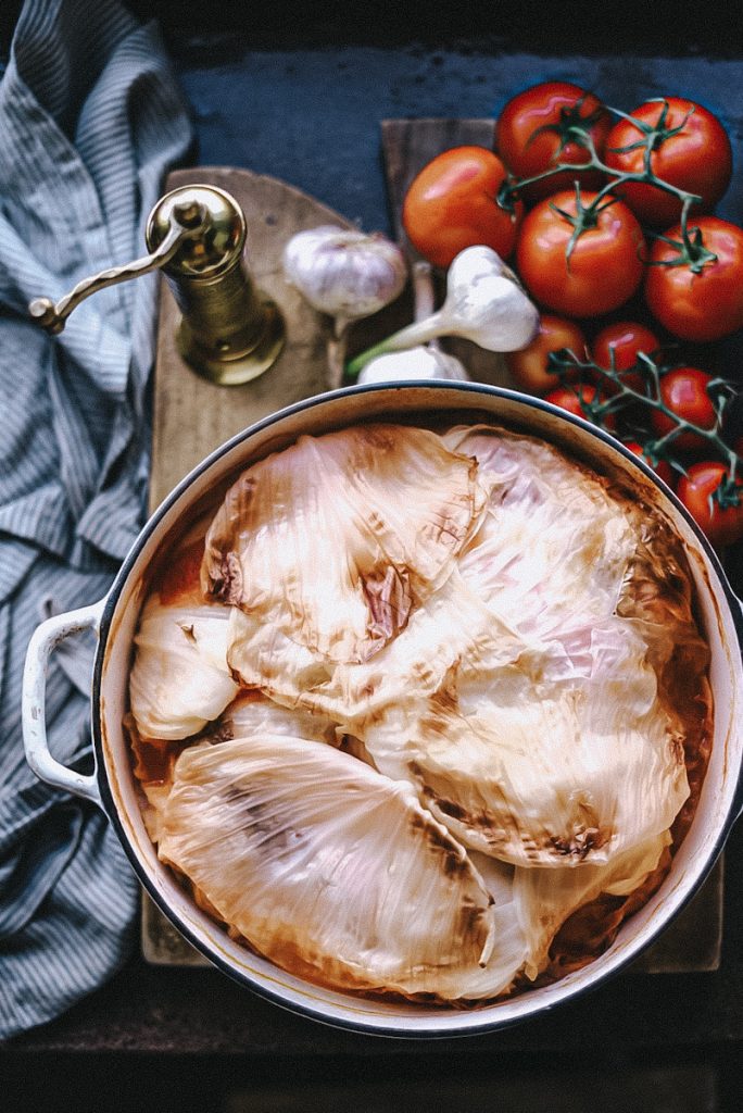 A large Dutch oven full of stuffed cabbage rolls that have been covered with cabbage leaves.
