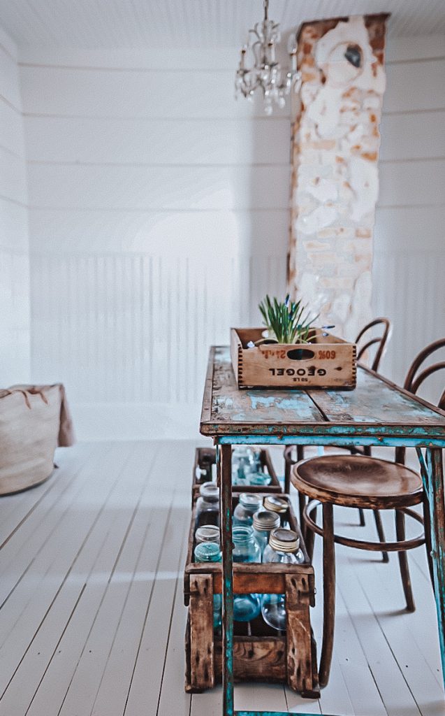 A beautiful room with a chippy antique table and a vintage wood box with plants on top.
