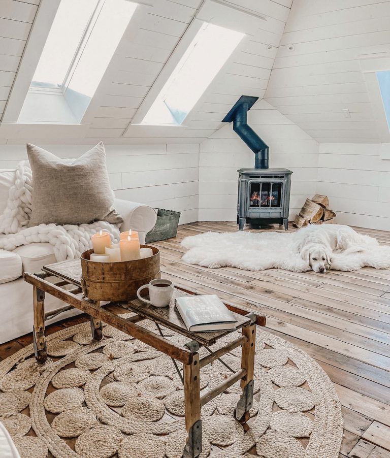 A cozy corner of a family room that is decorated with Scandinavian farmhouse style and has candles and a wood burning stove.