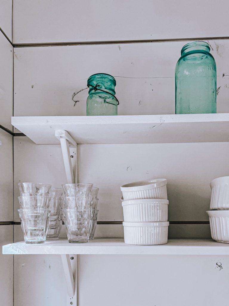 Organized shelves with glassware and bowls stacked neatly.