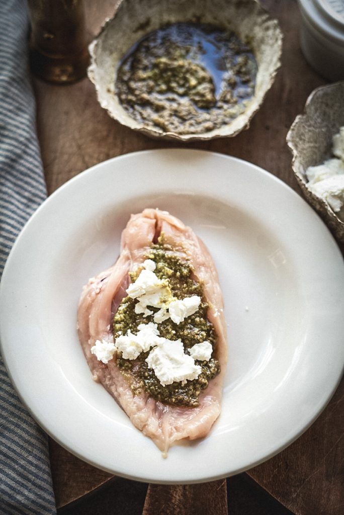 Goat cheese and pesto filling on a chicken breast that is about to be stuffed.