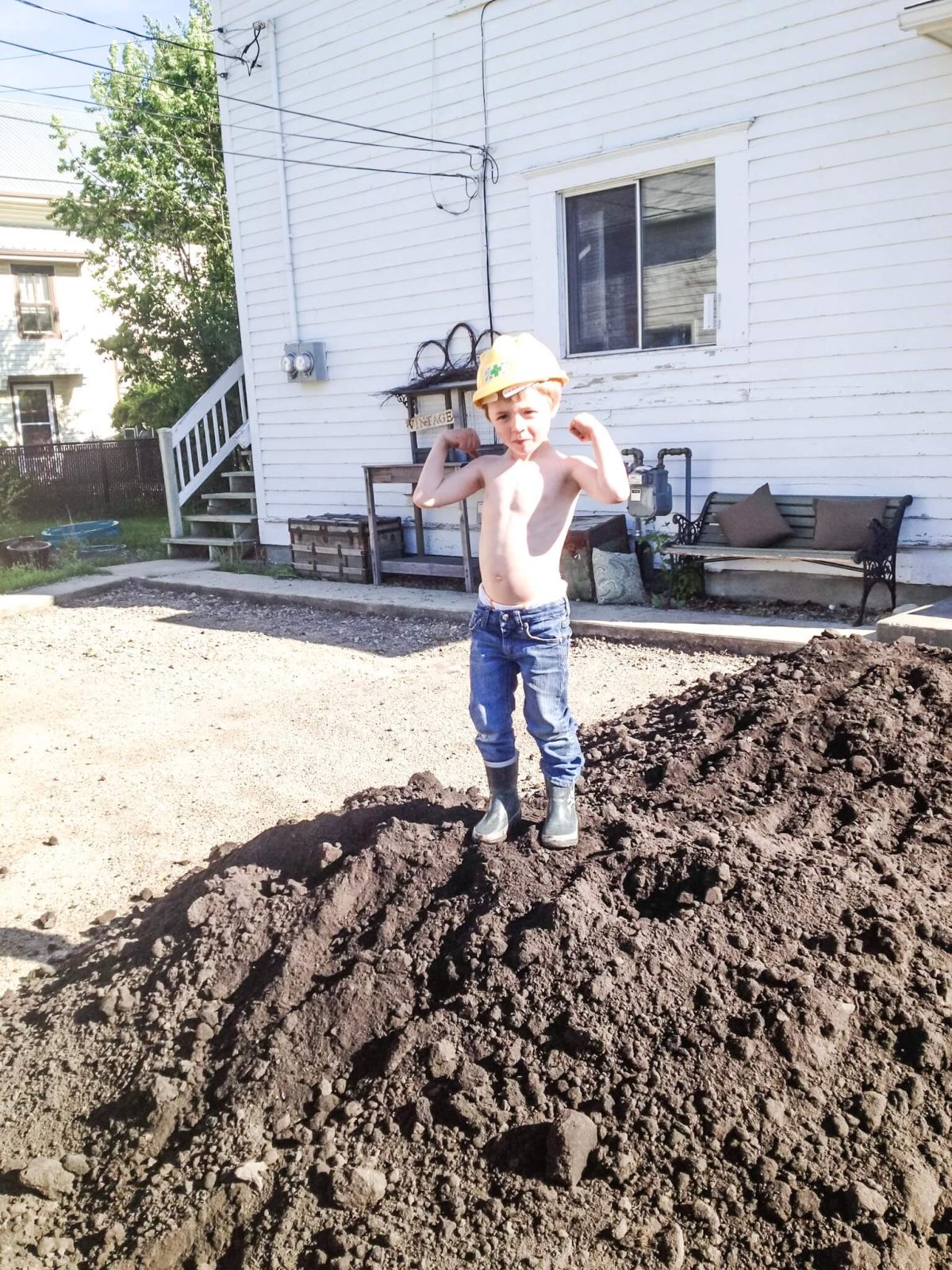 Young boy standing on a pile of dirt, helping with a home remodel.