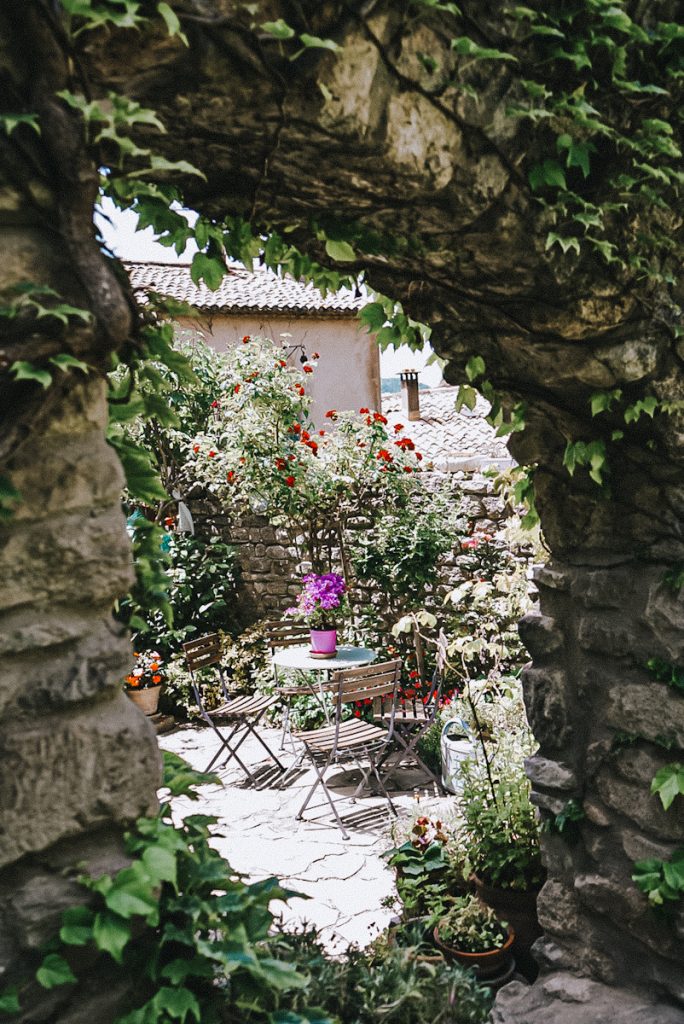 A beautiful secret garden in France with a bistro table and flowers.