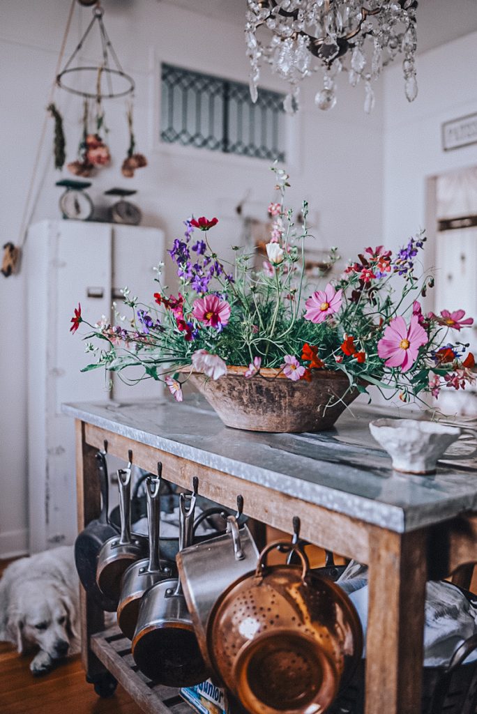 Flowers in a vintage container on a kitchen island.
