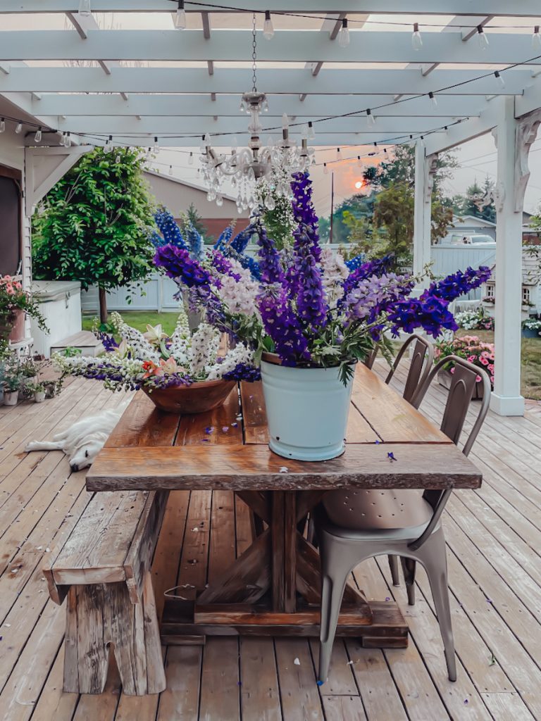 An outdoor table with purple flowers on top.