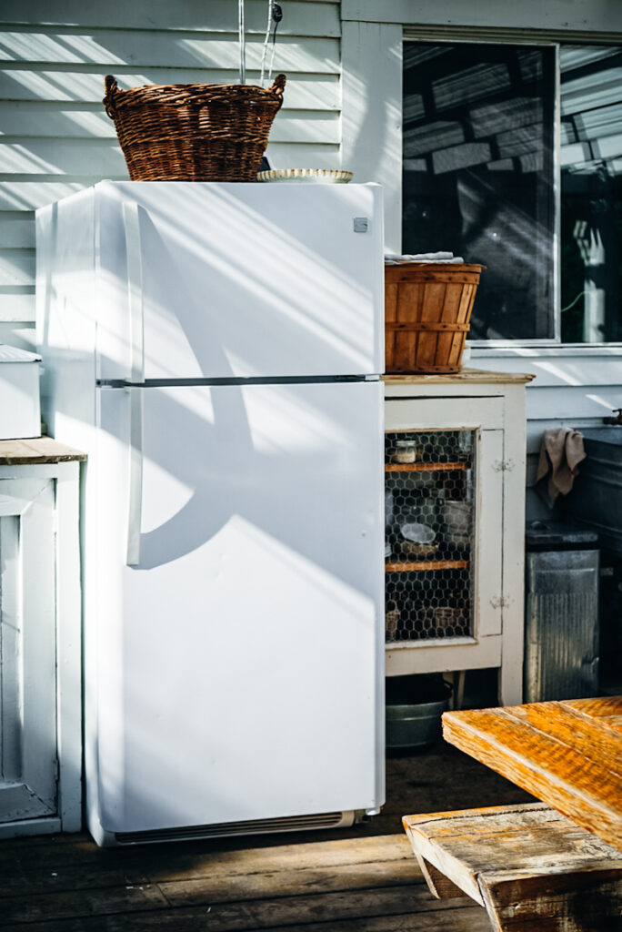 A fridge with storage baskets on it being used in an outdoor kitchen space.