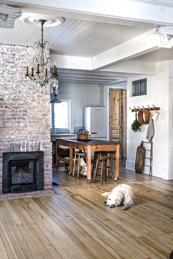 View of a cozy exposed brick fireplace at the entrance of a Scandinavian kitchen.