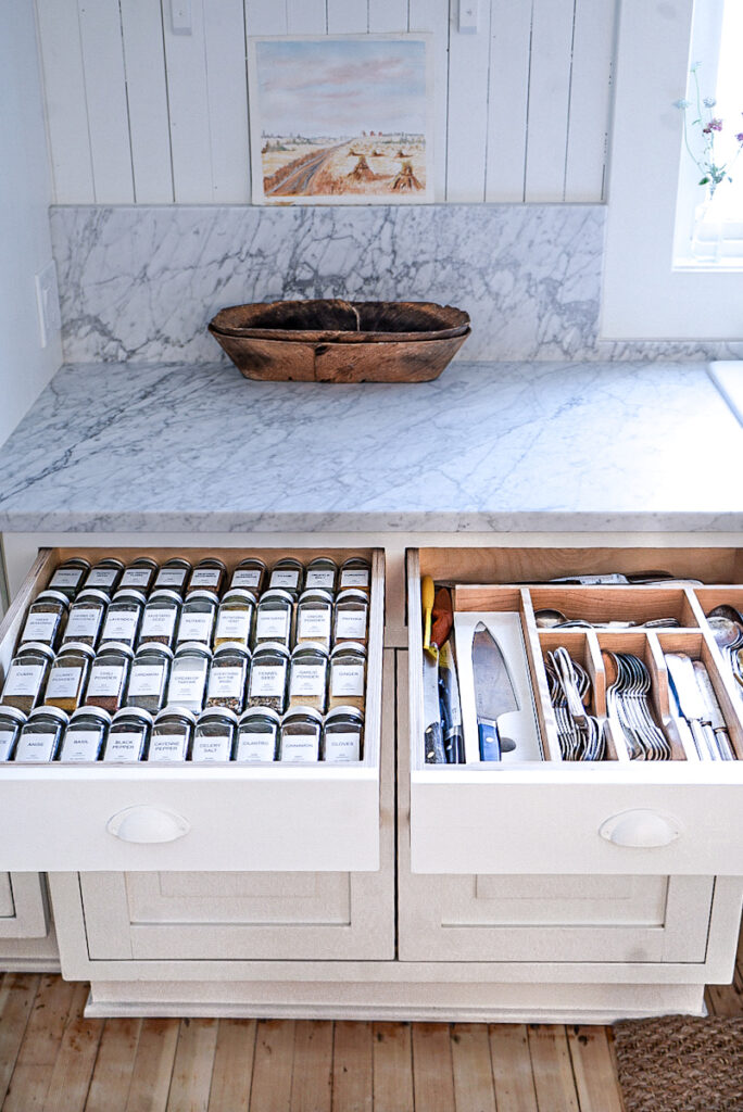 Drawers with wooden organizers in a white kitchen.