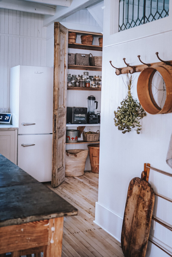 Tall wood doors in a pantry that is organized in a Scandinavian kitchen.