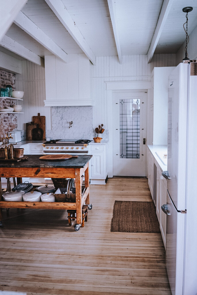 Beautiful view of a white kitchen with natural light, an open concept island and white range.