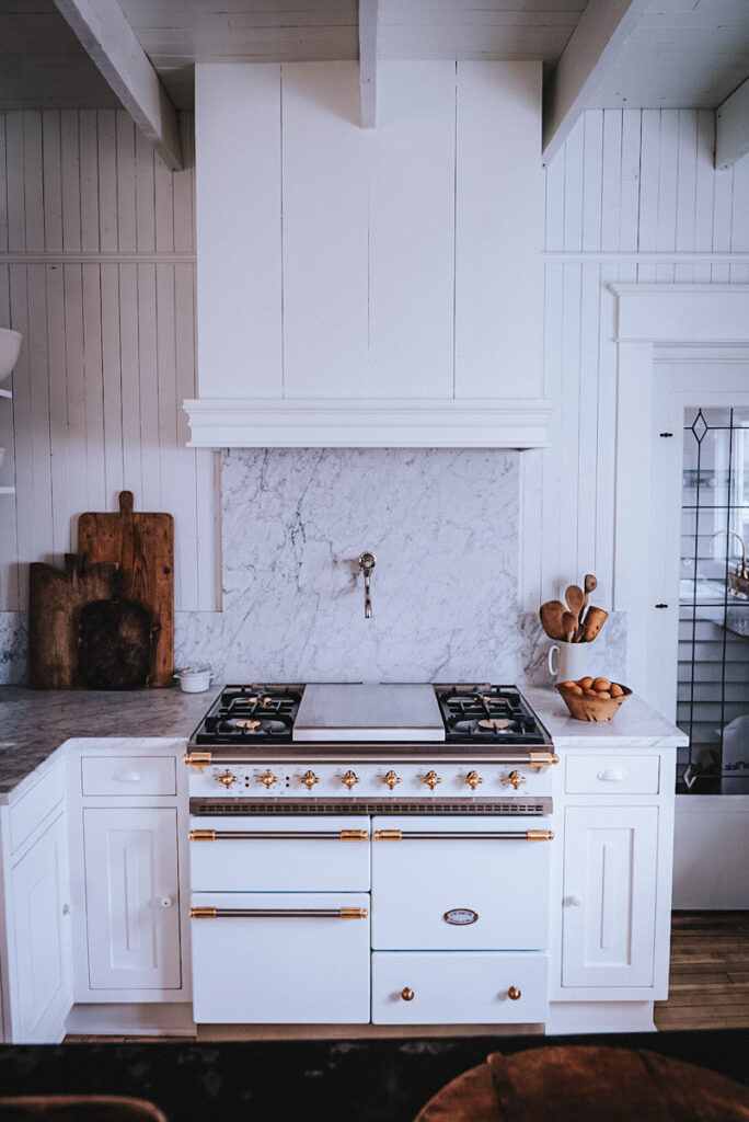 White Lacanche Chagny stove with brass and stainless steel metal mixed hardware in a white Scandinavian kitchen.