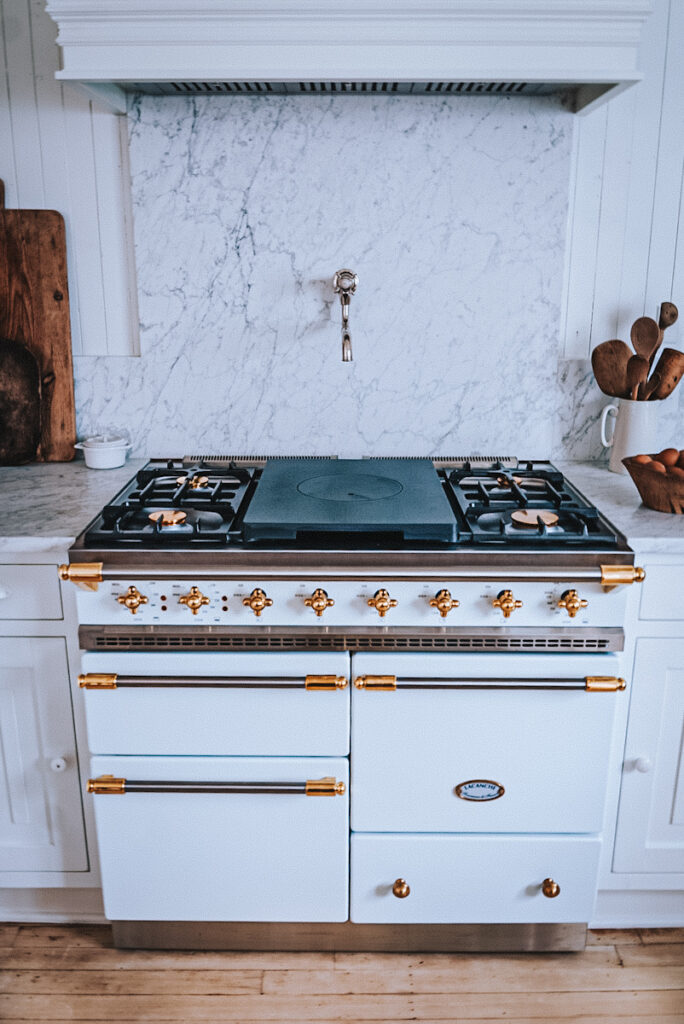 White Lacanche Chagny stove with a Carrara marble backsplash and a Waterworks pot filler.