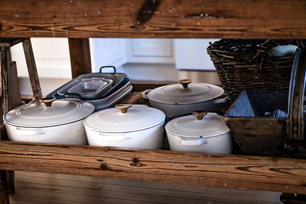 Cast iron dutch ovens stoved in the open concept kitchen island that is made of wood.