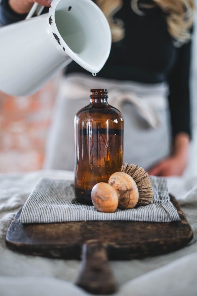 Filling a glass spray bottle with water and Castile soap to make homemade all purpose cleaner.