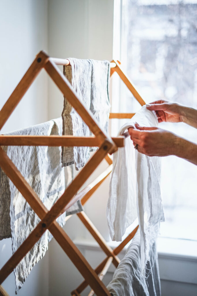 Hanging freshly washed linens on a wooden drying rack.