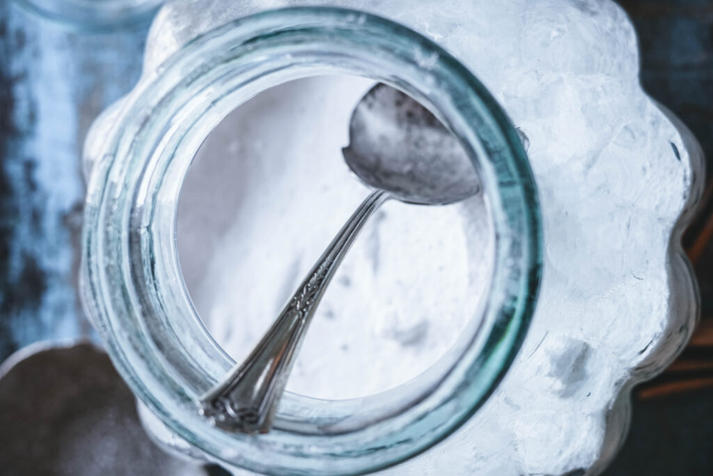 DIY Laundry powder in a blue jar with a silver spoon.