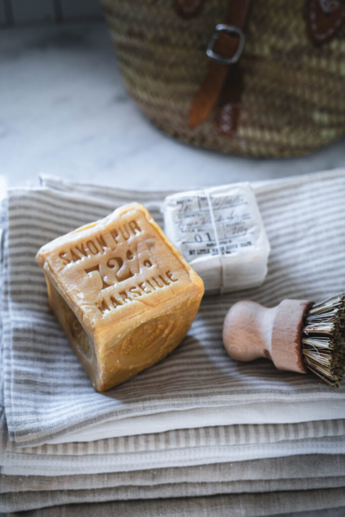 Marseille soap and a scrub brush used for removing stains on laundry.