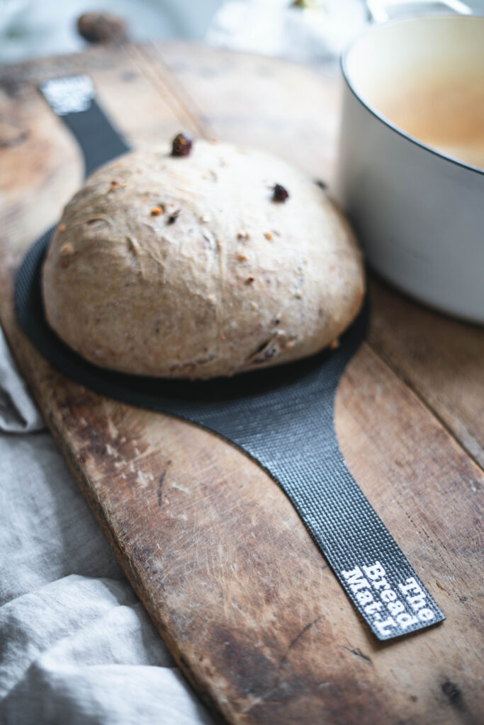 A freshly baked loaf of bread on on a bread mat.