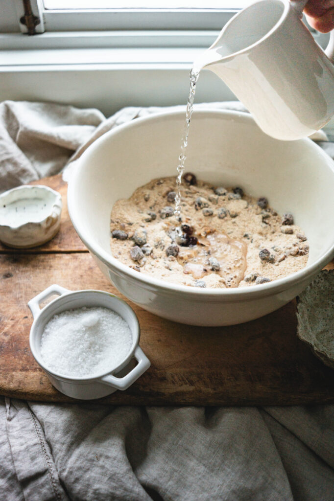 Adding water to cranberry walnut bread ingredients.