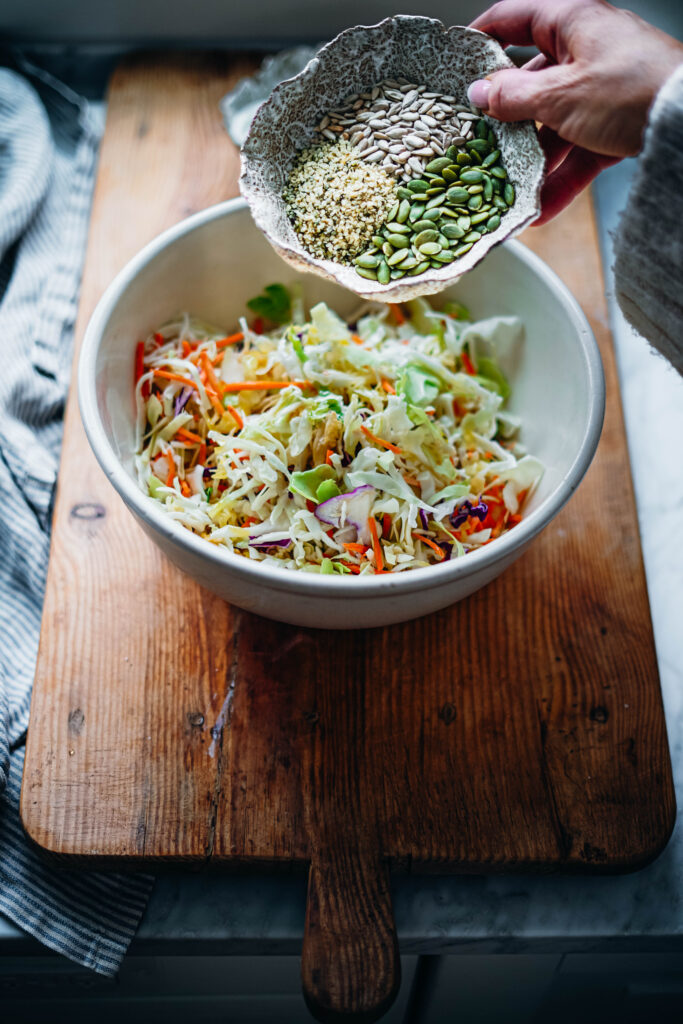 Adding hemp seeds, sunflower seeds and pumpkin seeds to add a nutritious crunch to a healthy coleslaw.