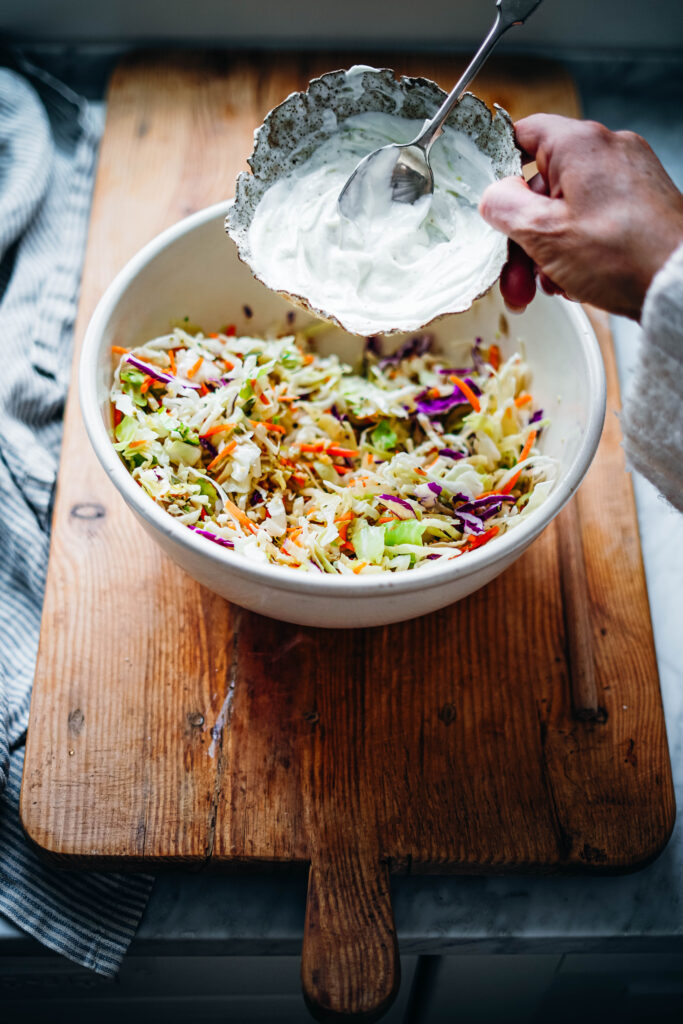 Mixing a healthy coleslaw dressing that is made of Greek yogurt, honey and apple cider vinegar for a delicious salad.